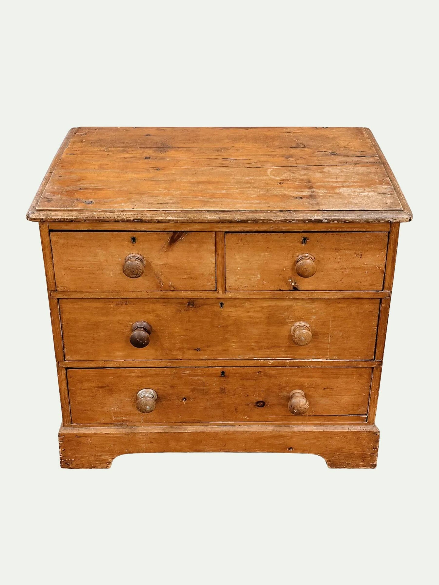 A vintage wooden chest of drawers with three front drawers, round metal knobs, and a flat top, shown against a plain light background.