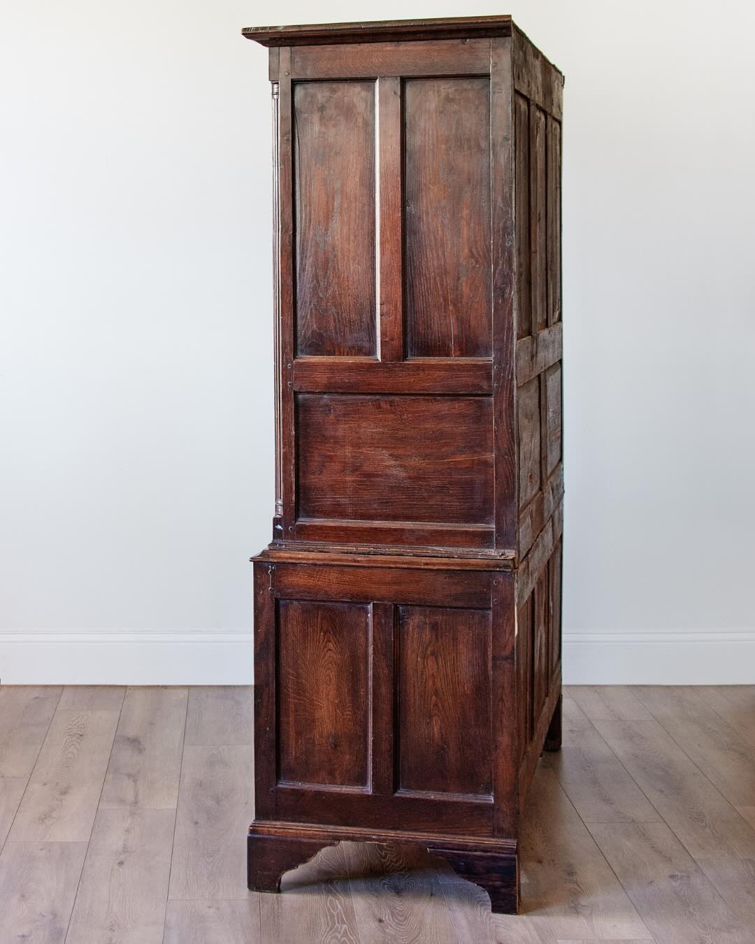side view of antique English oak cupboard with paneled doors and drawers