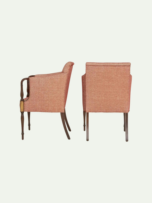 Two upholstered armchairs shown from the back on a plain light background. The chairs have textured peach-pink fabric seats and backs with dark brown wooden legs and armrests.