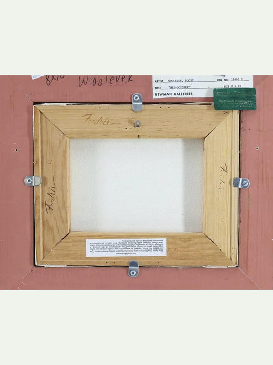 Back side of a framed artwork showing a light wood frame mounted on a reddish-brown backing board, with mounting hardware, labels, and handwritten notes visible.
