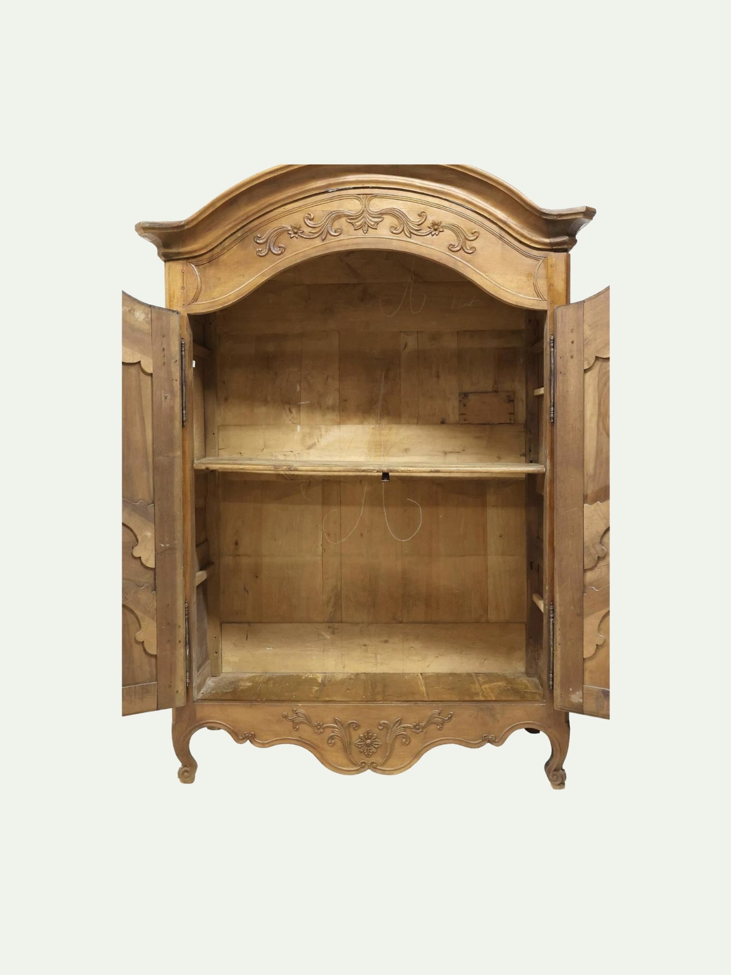 An antique carved wooden armoire cabinet with open doors, showing a rustic finish and a single interior shelf, set against a plain off-white background.