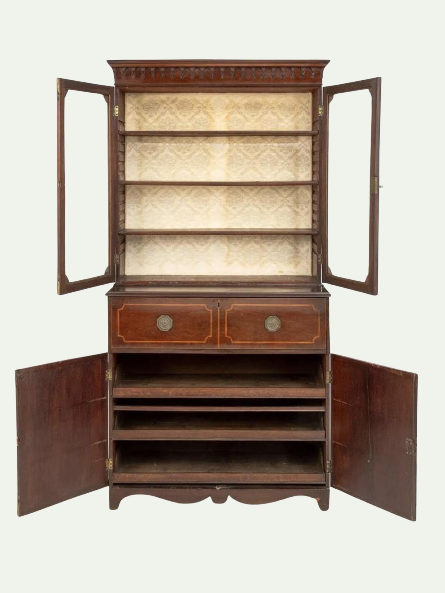 An antique dark wood cabinet with glass doors, open to show a patterned beige lining on the upper shelves and open lower compartments, set against a solid off-white background.