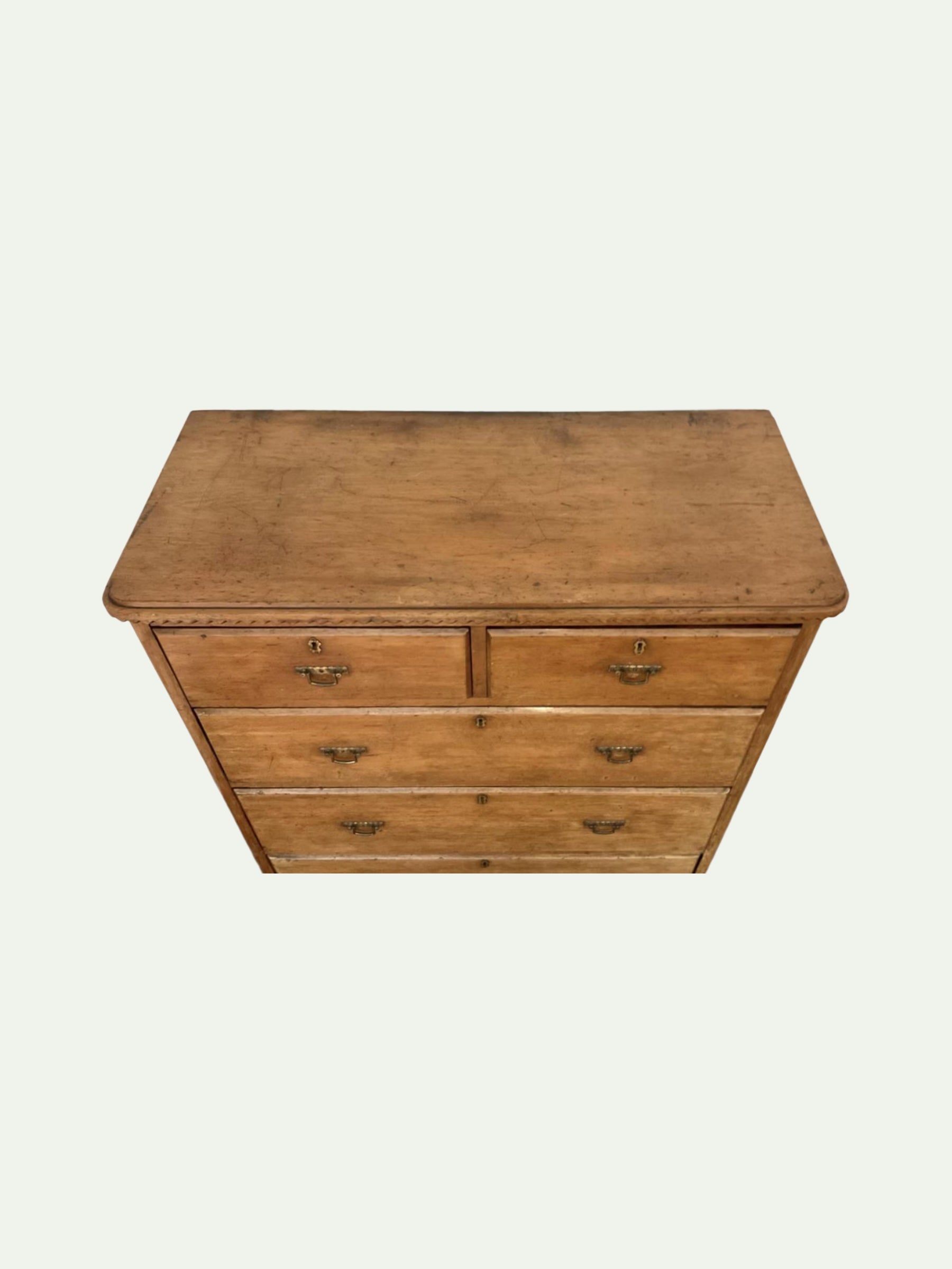 A vintage wooden chest of drawers with five drawers and brass handles, shown from a top-down perspective against a light off-white background.