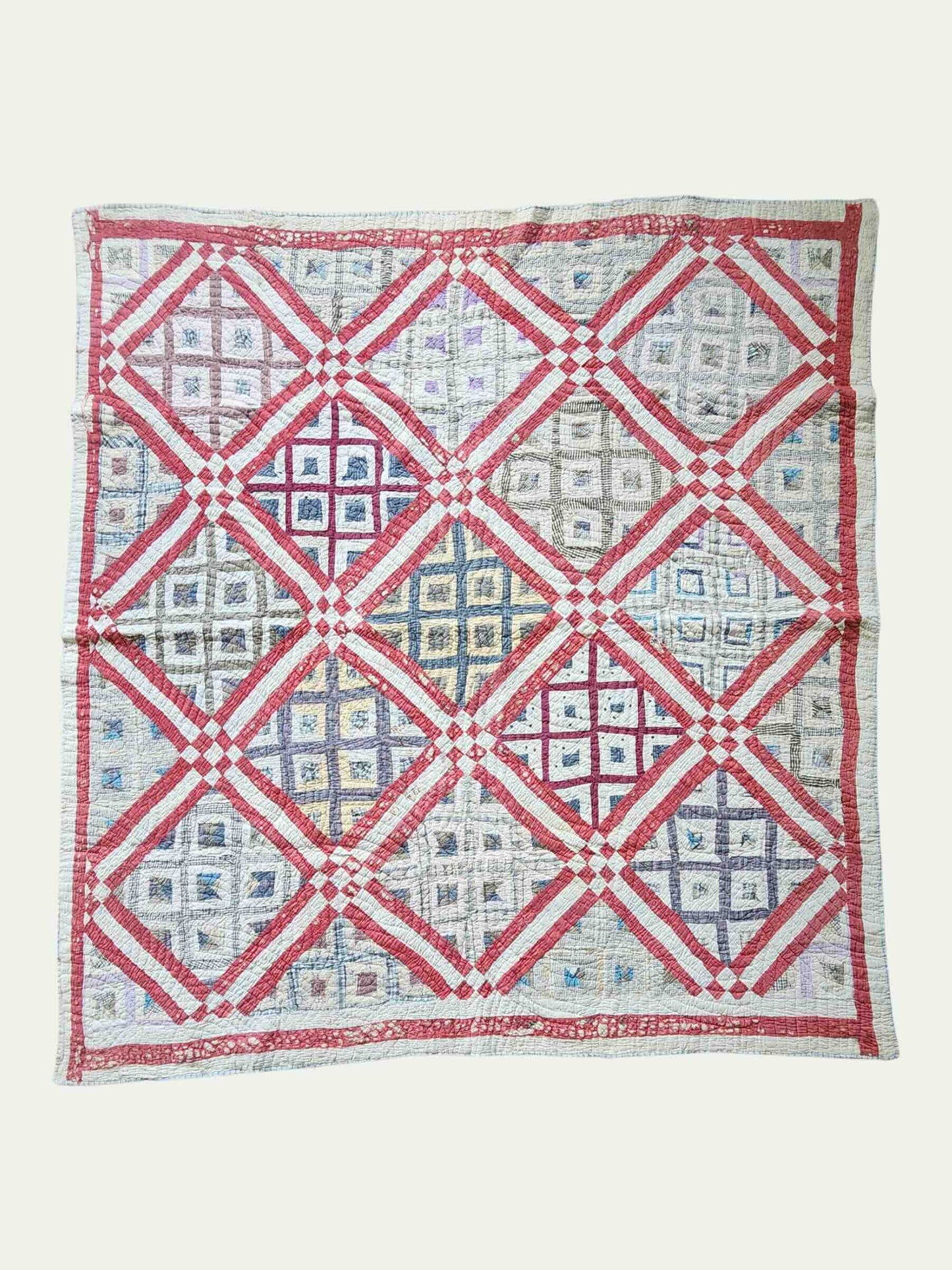 Quilt with red and white geometric pattern on a white background