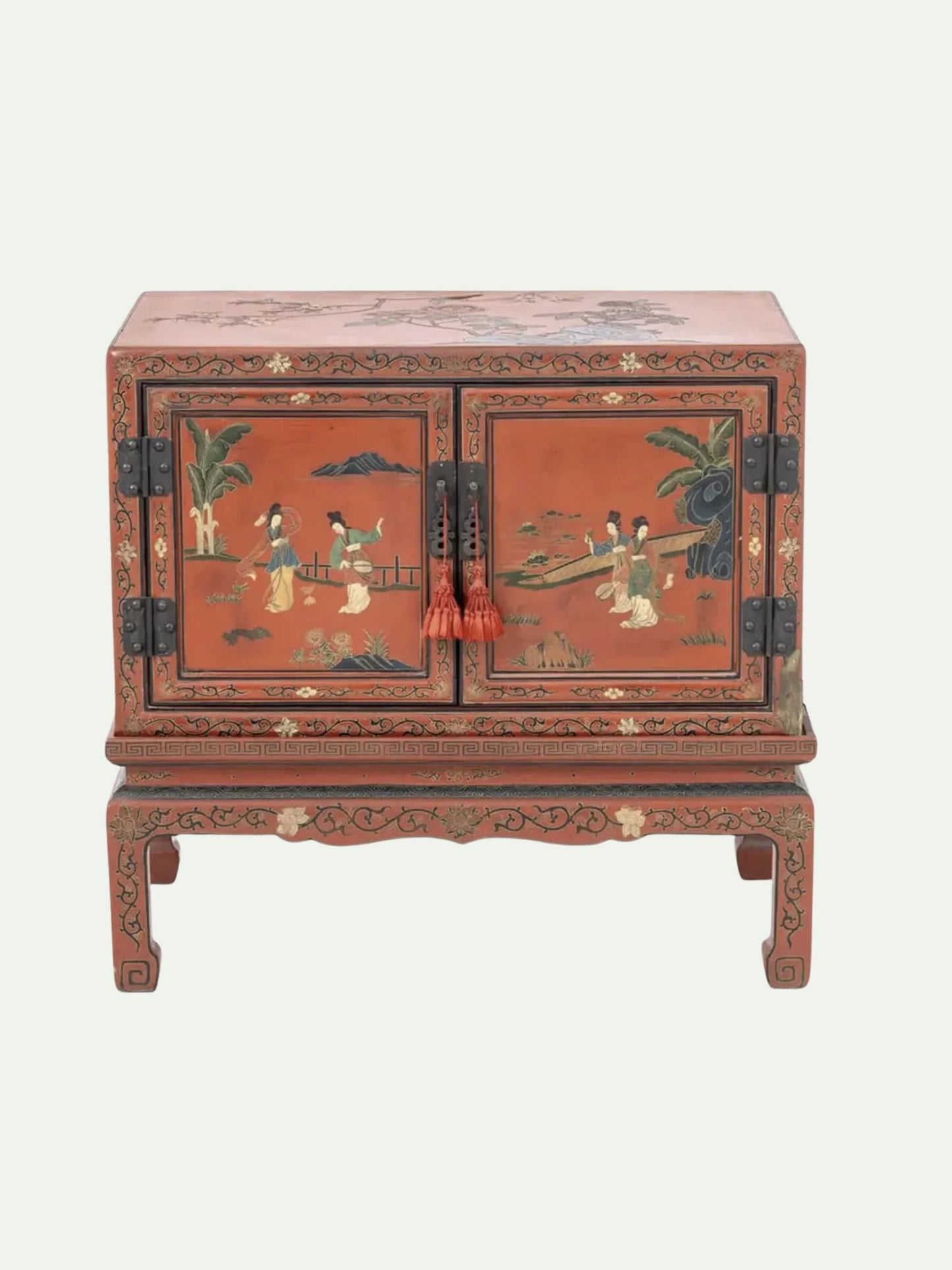 A traditional Chinese lacquered cabinet with a reddish-brown finish and hand-painted figures on the doors, featuring black metal hinges and red tassels on the front.