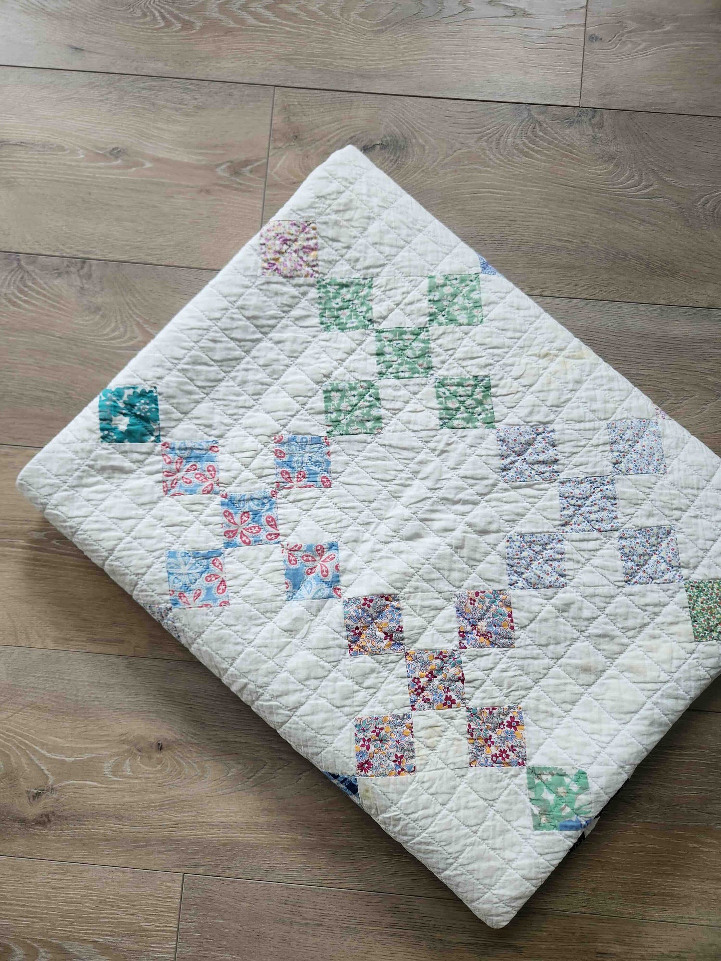 Quilt with colorful patchwork design on a wooden floor