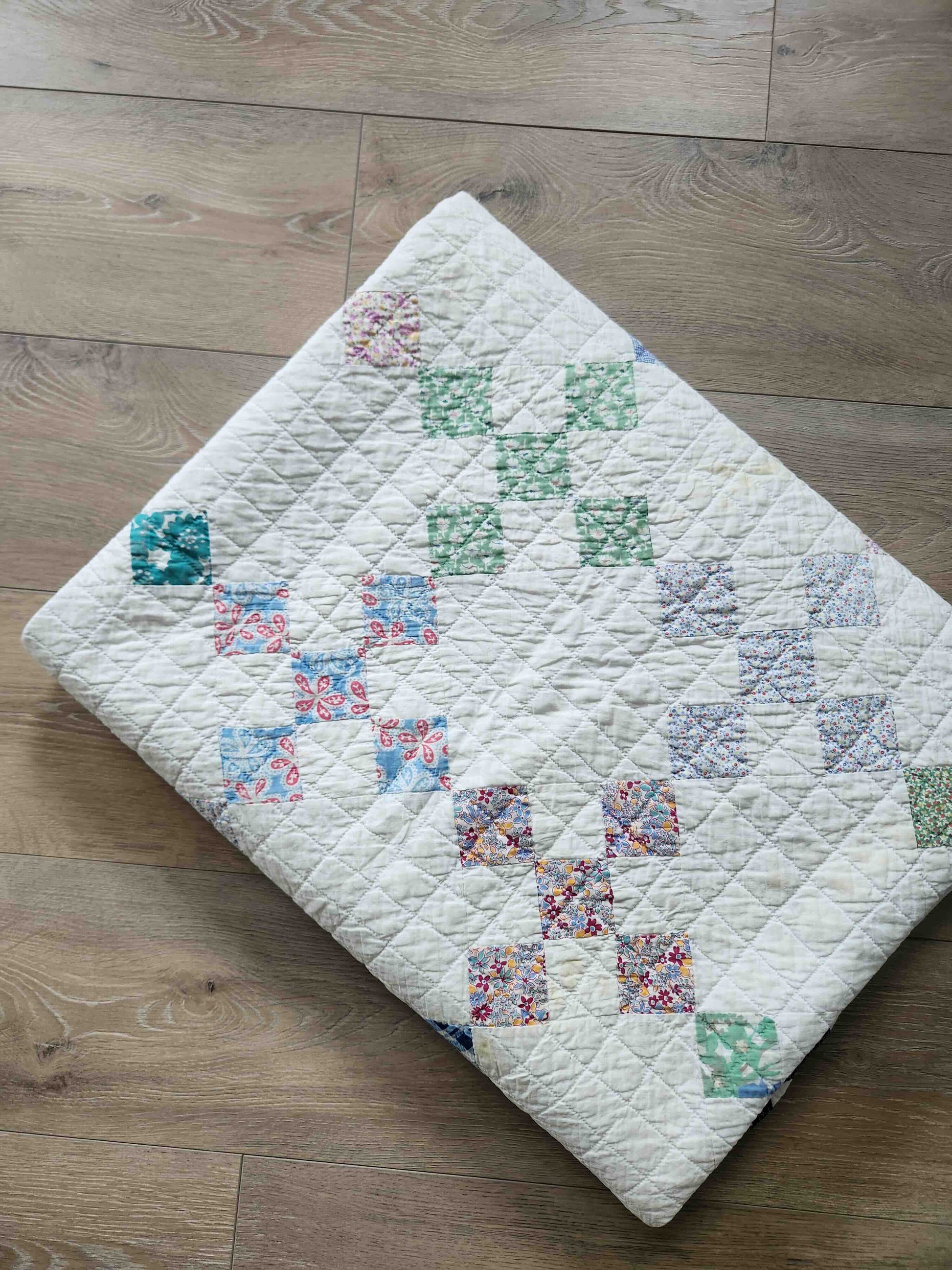 Quilt with colorful patchwork design on a wooden floor