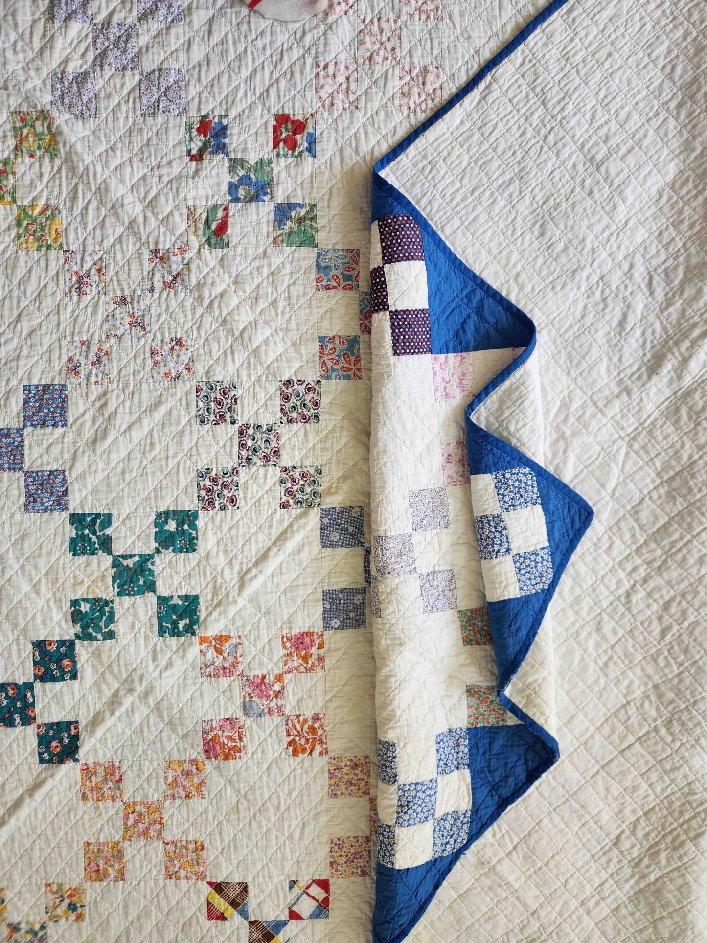 Quilt with a patchwork design featuring various colors on a bed.