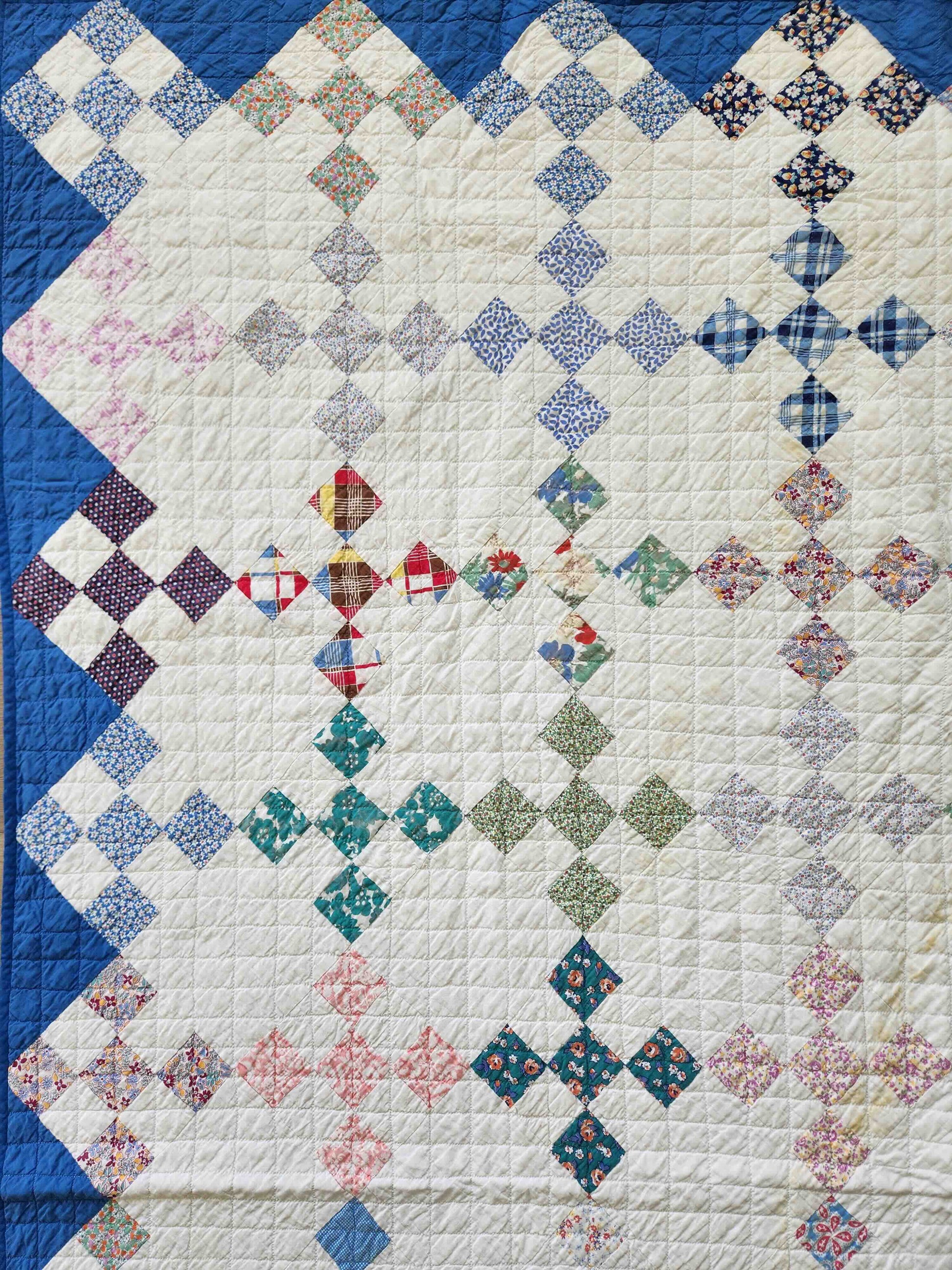 Quilt with diamond and star pattern in various colors on a white background