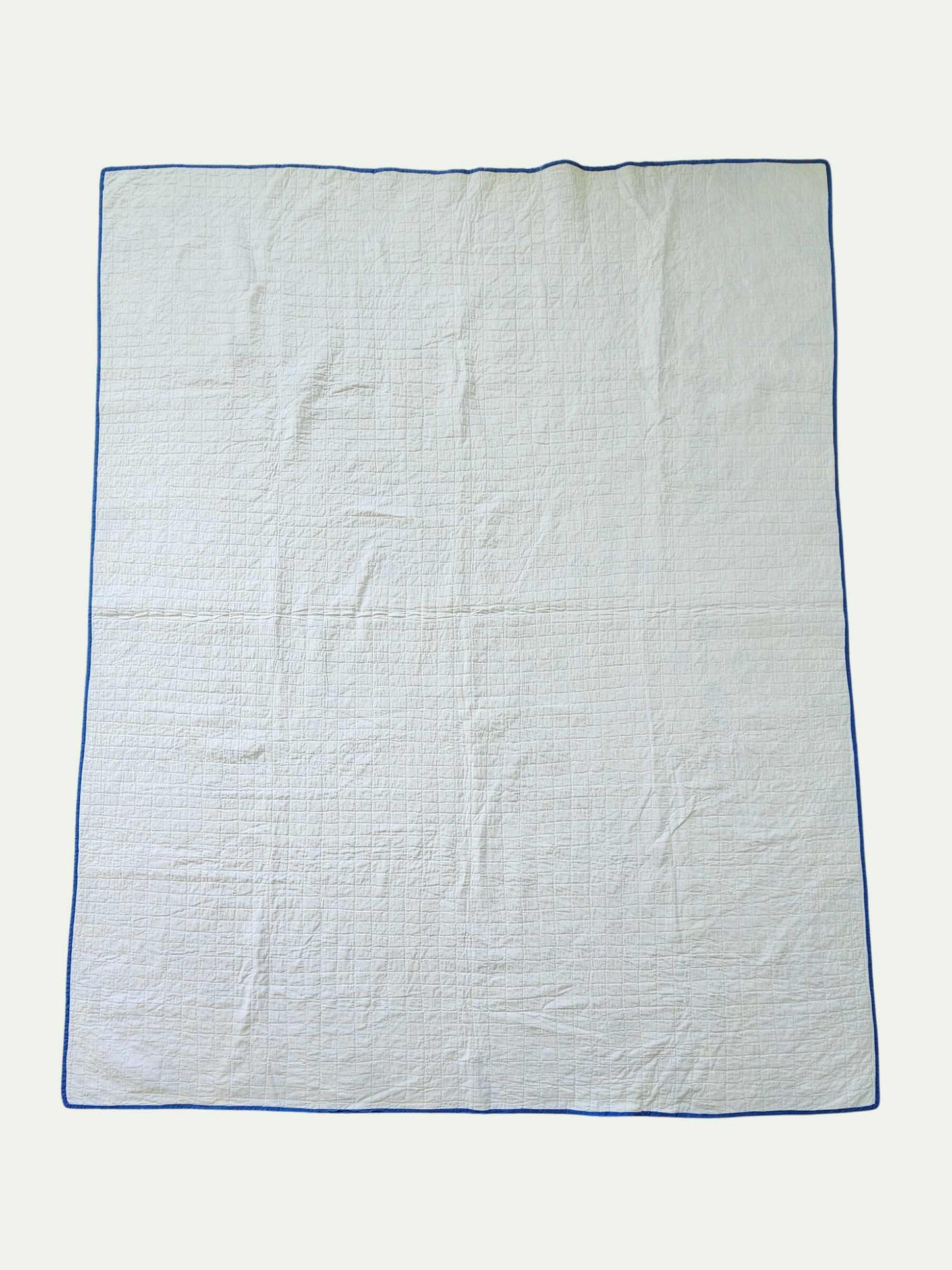 White quilt with blue border on a white background