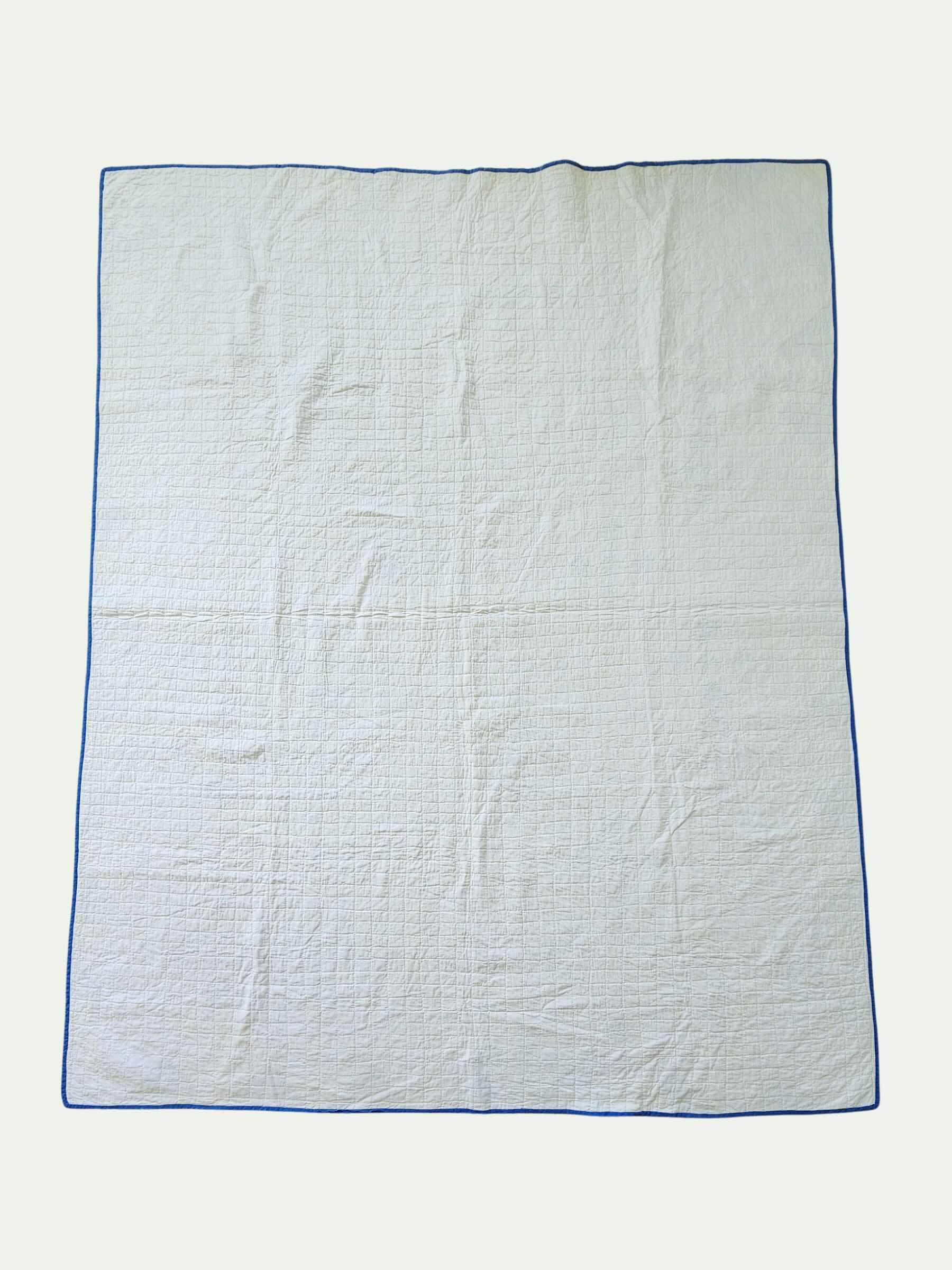 White quilt with blue border on a white background