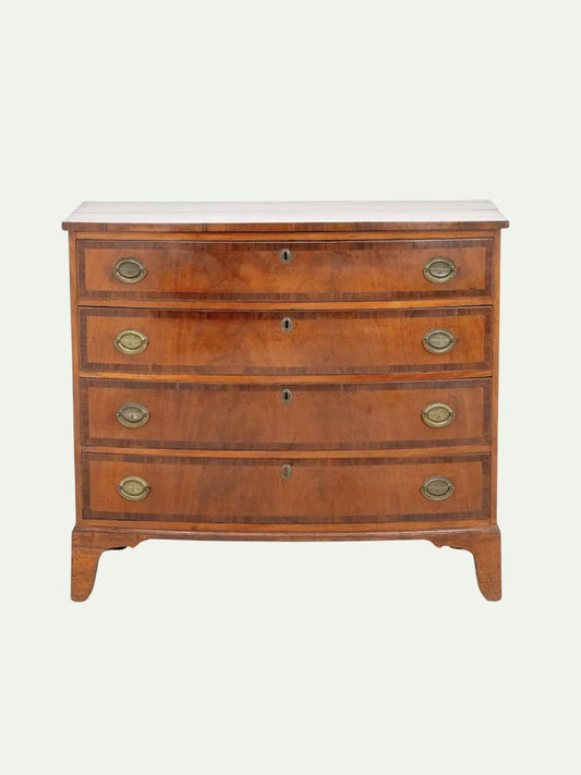 A vintage wooden chest of drawers with five drawers, featuring a warm brown wood finish, brass handles, and keyholes, set against a plain light background.
