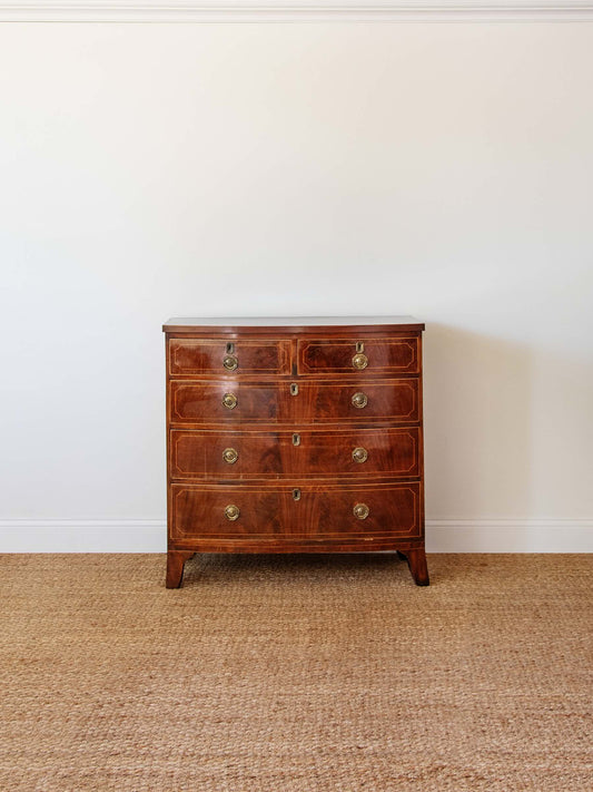 Wooden dresser with four drawers on a beige carpet against a white wall
