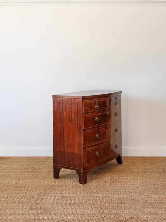 Wooden dresser with four drawers on a textured floor against a white wall