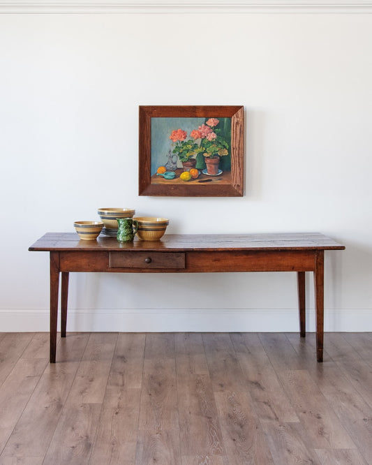 wooden French farmhouse table with drawer and floral art above it