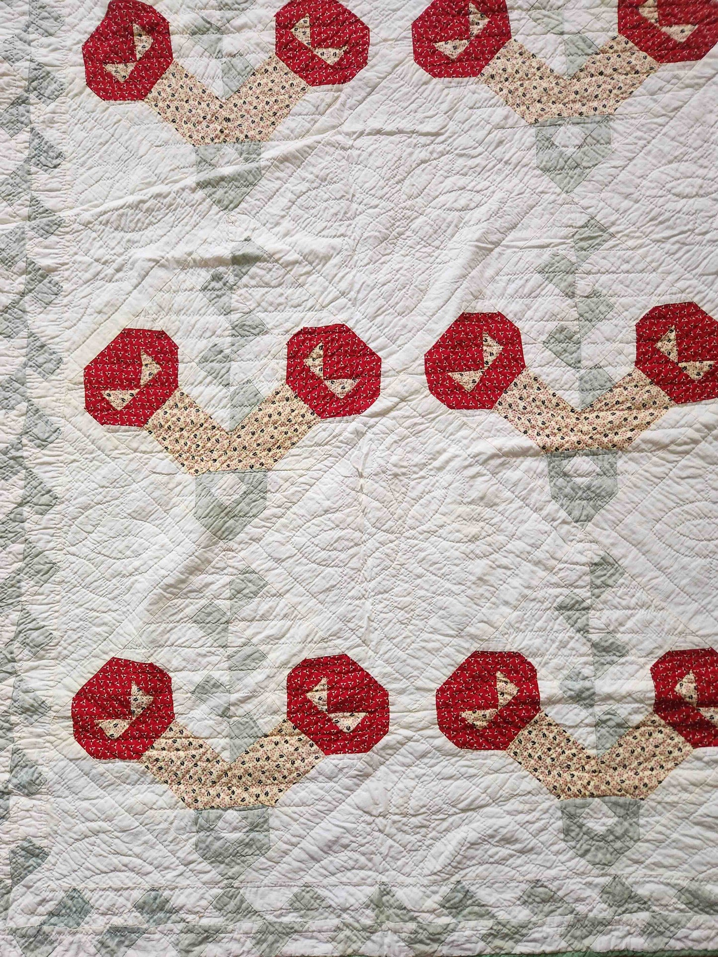 Quilt with red and beige geometric pattern on a textured fabric background