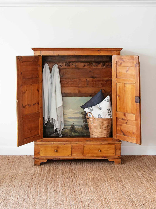 wooden dresser with blankets and pillows inside 
