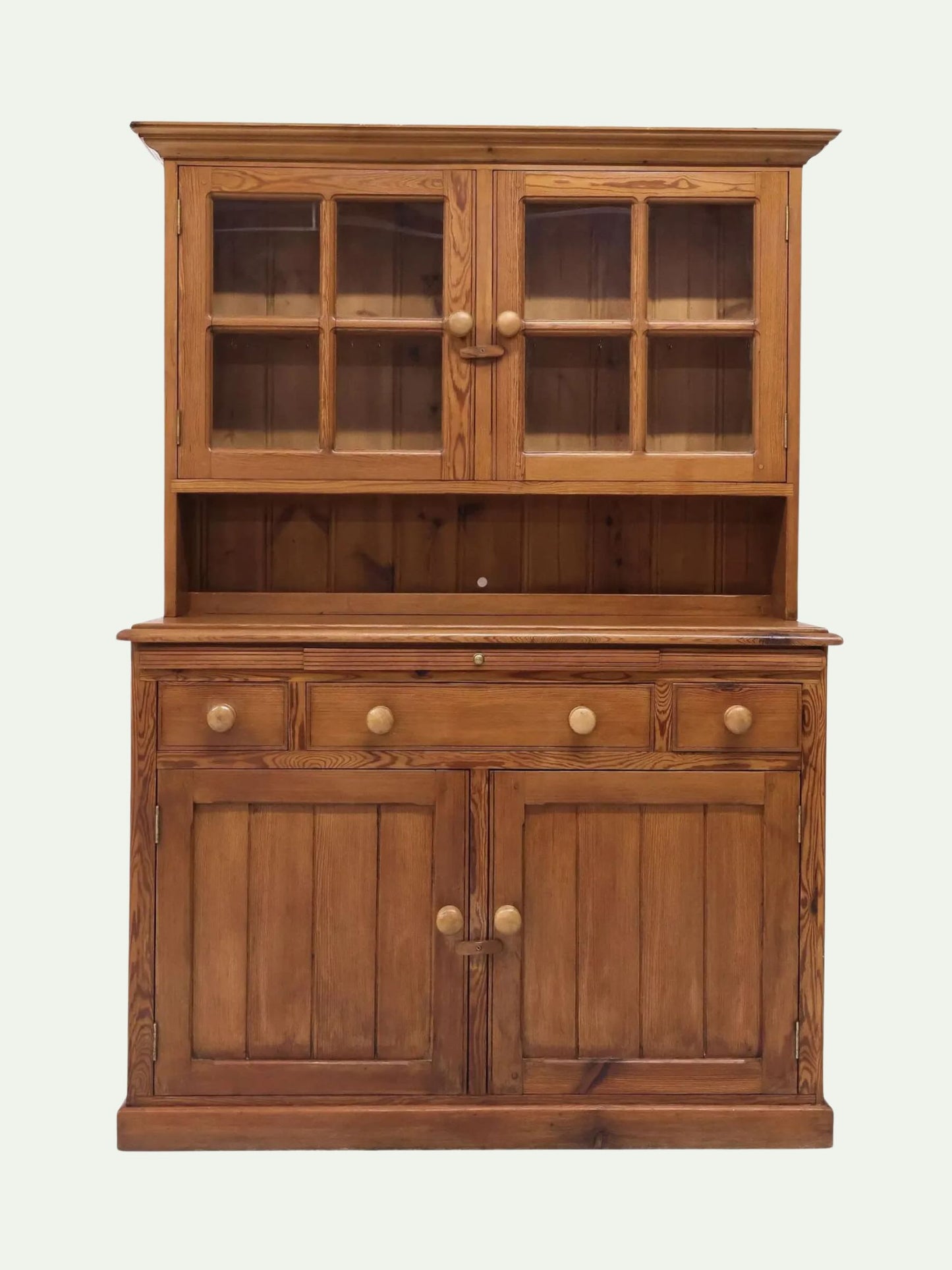 A rustic wooden hutch cabinet with a warm medium-brown finish, featuring a glass-front upper cabinet, an open shelf, three drawers, and two lower cabinet doors with round wooden knobs, set against a plain off-white background.