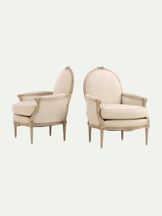 Pair of beige armchairs with decorative wooden frames on a white background