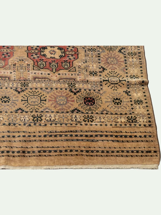 A traditional oriental-style area rug with a beige base and intricate geometric patterns in red, black, and blue, shown folded to display its pattern and texture.