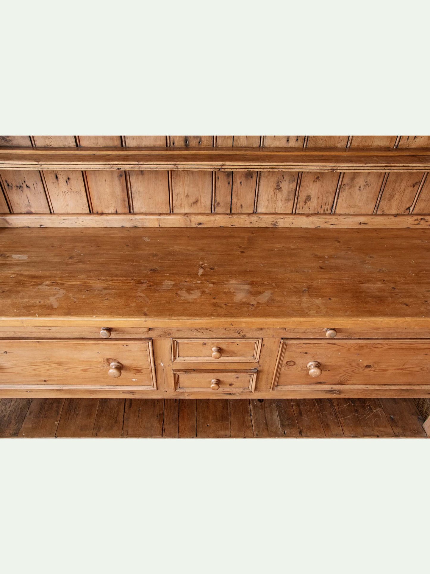 A rustic wooden bench with a three-drawer front, small round knobs, and a matching wooden backrest, shown against a light off-white background.