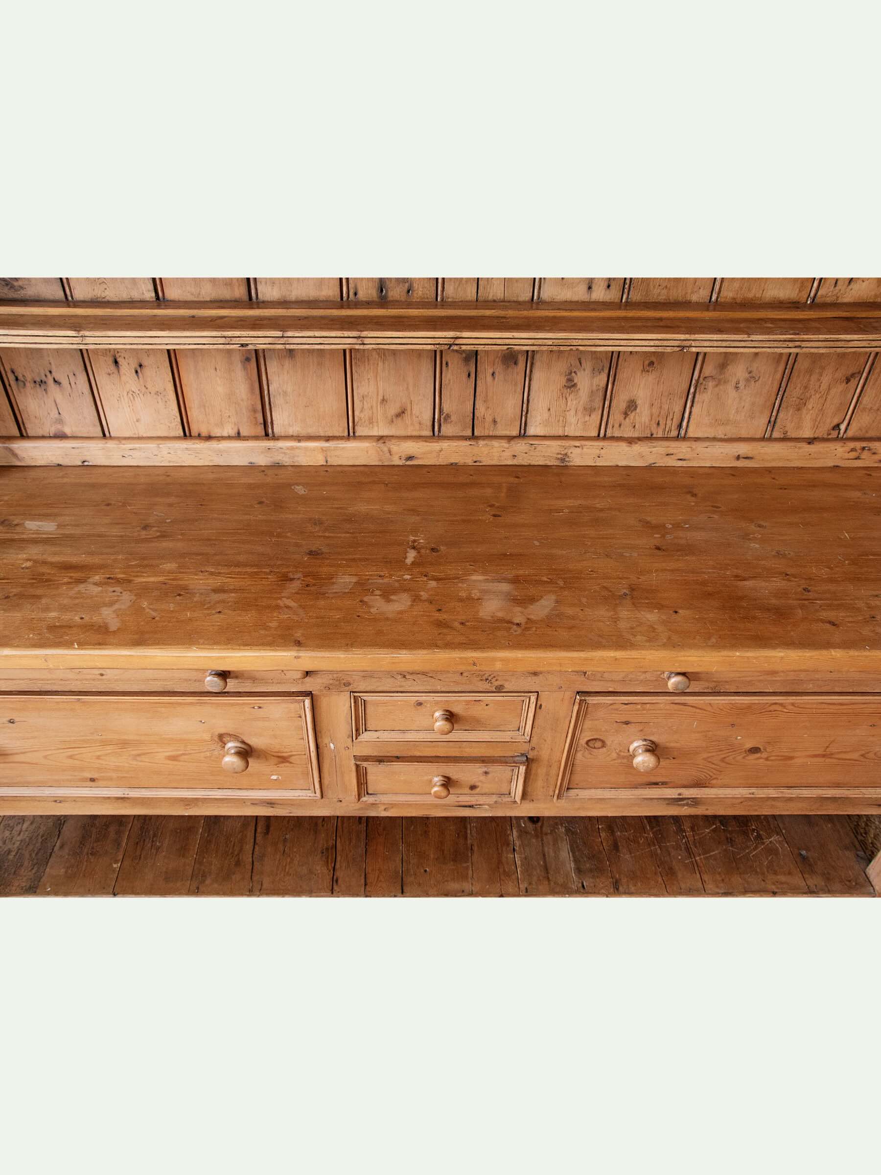 A rustic wooden bench with a three-drawer front, small round knobs, and a matching wooden backrest, shown against a light off-white background.
