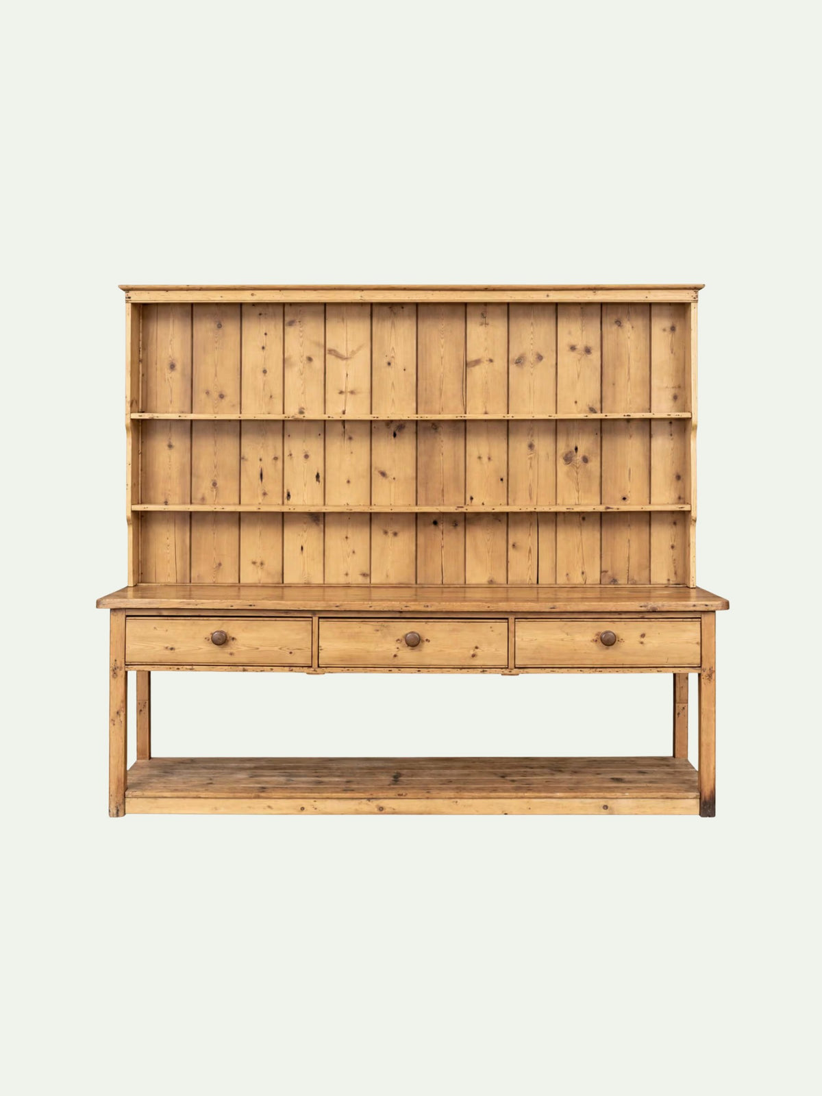 A light natural pine hutch with three open shelves on the upper section, three drawers with round metal knobs on the lower section, and a lower open shelf, shown against a plain off-white background.