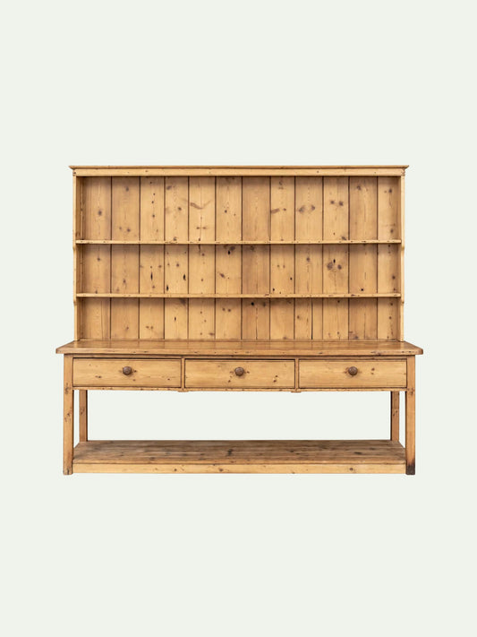 A light natural pine hutch with three open shelves on the upper section, three drawers with round metal knobs on the lower section, and a lower open shelf, shown against a plain off-white background.