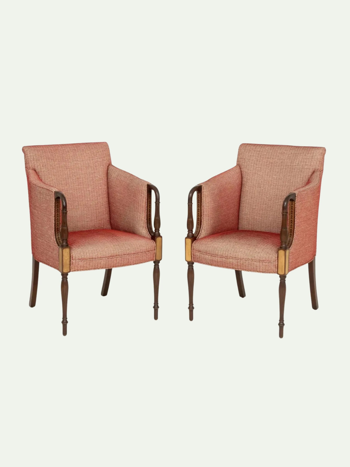 A pair of vintage-style armchairs upholstered in a textured dusty rose pink fabric, featuring dark brown wooden arms and legs with brass accents, set against a solid off-white background.
