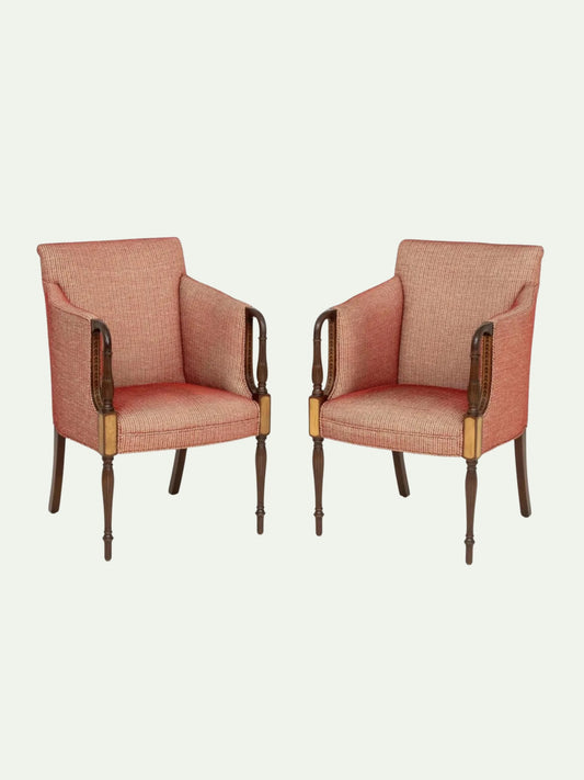 A pair of vintage-style armchairs upholstered in a textured dusty rose pink fabric, featuring dark brown wooden arms and legs with brass accents, set against a solid off-white background.
