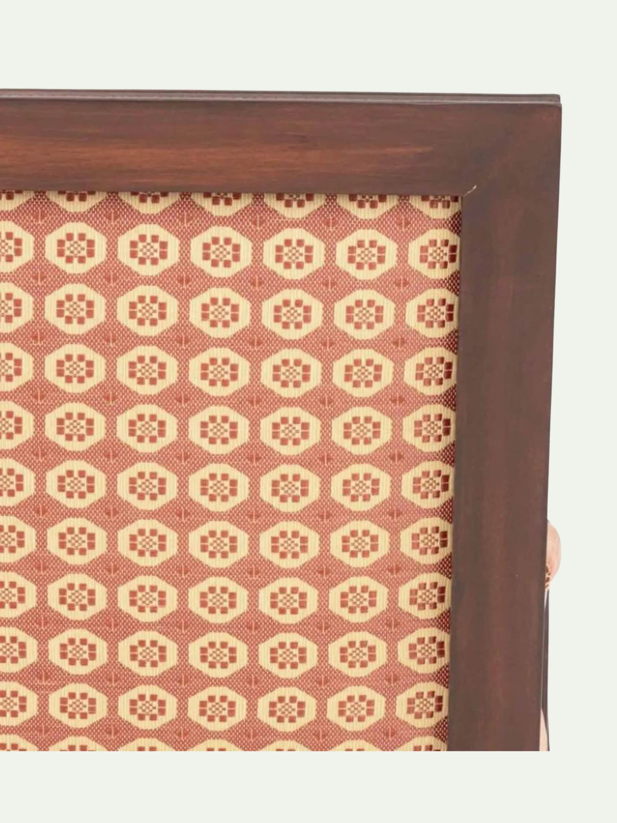 A close-up of a dark brown wooden frame with a woven fabric insert featuring a repeating geometric pattern in terracotta and cream.