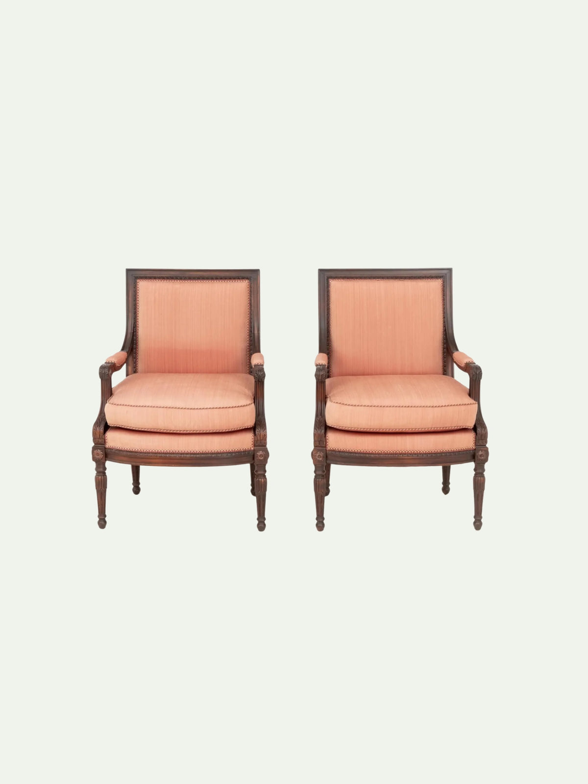 A pair of matching armchairs with peach-pink striped upholstery and dark brown wooden frames, shown against a solid off-white background.