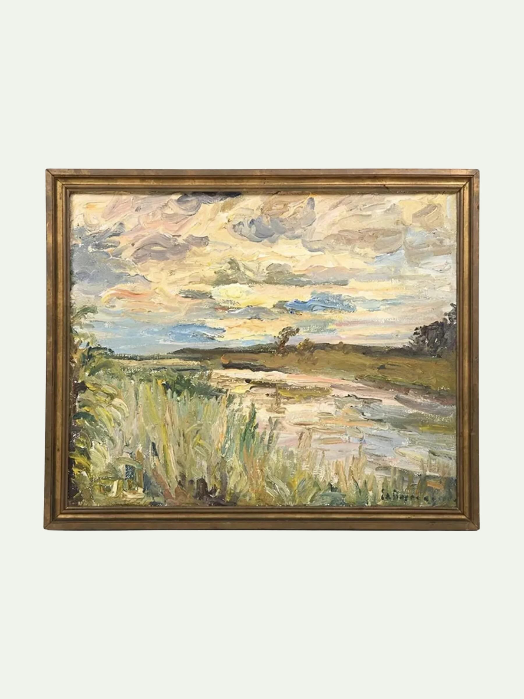 A framed landscape oil painting featuring a grassy field and a winding river under a cloudy sky, enclosed in a distressed gold frame against a light gray background.